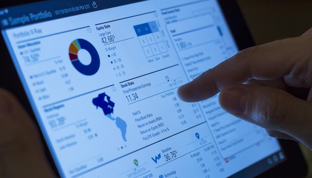 Woman pointing iPad displaying finance figures. 