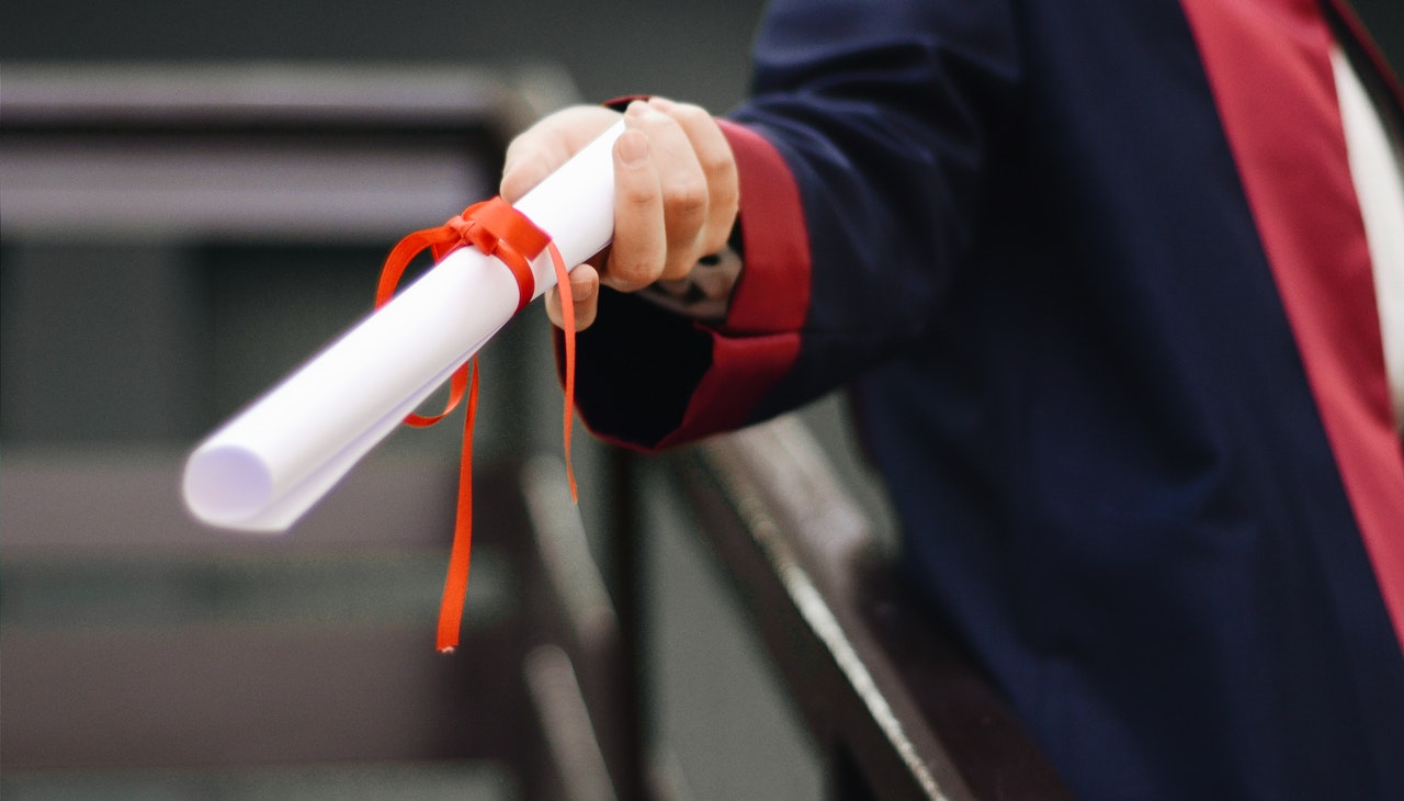 Graduate student holding a diploma. 