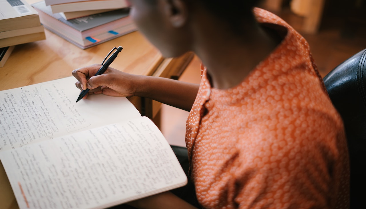 Student writing on a notebook. 