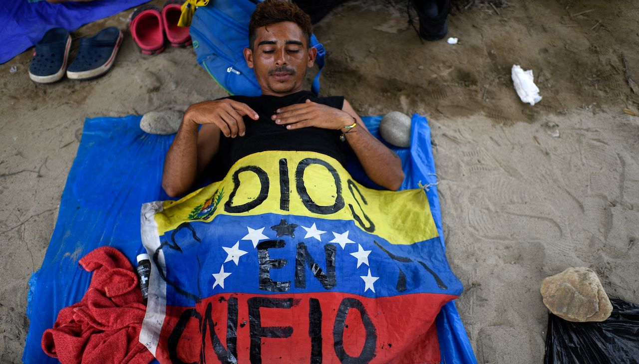 A Venezuelan migrant in Mexico sleeps under his flag on the journey to the U.S.-Mexico border. Photo: Pedro Pardo/AFP via Getty Images.