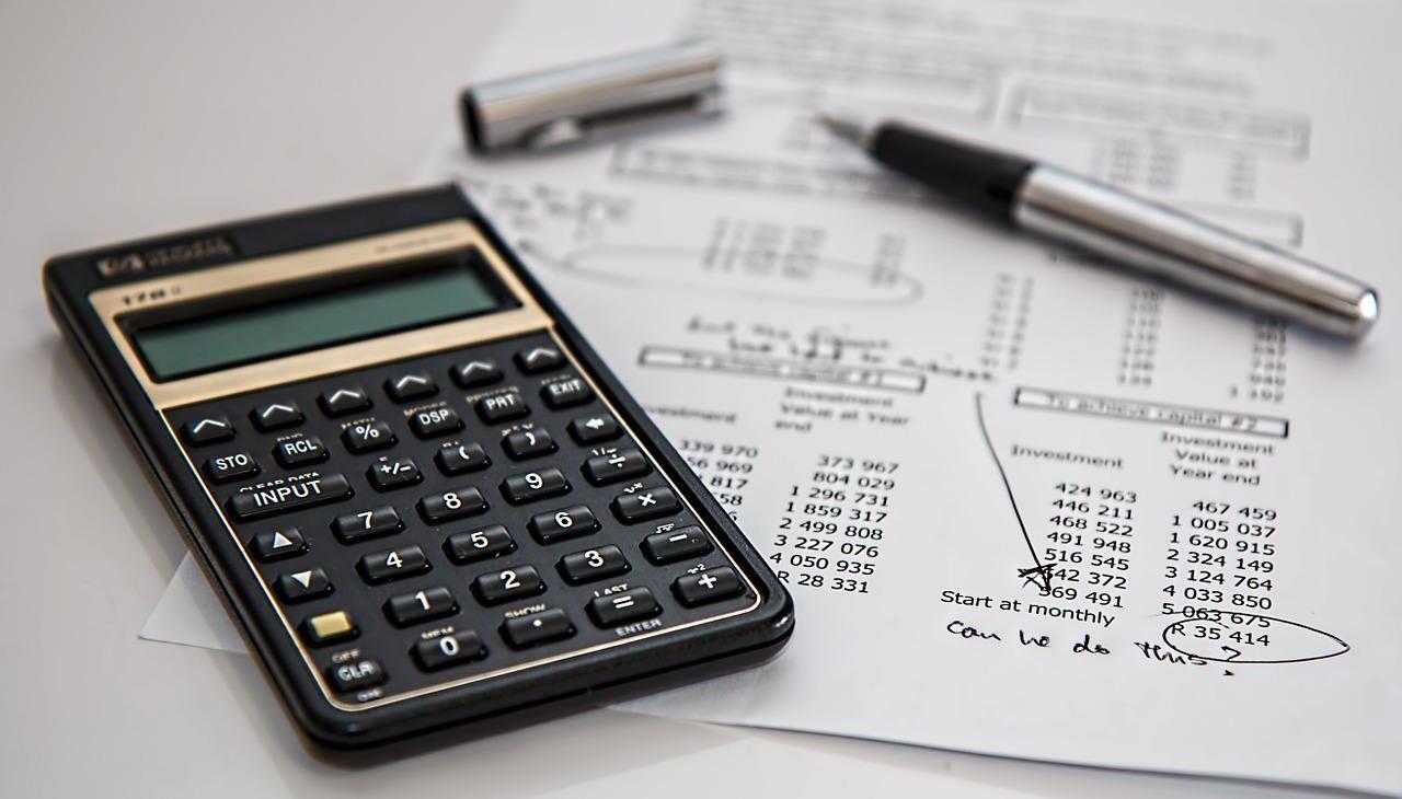 A calculator and a pen above a sheet with numbers and figures. 