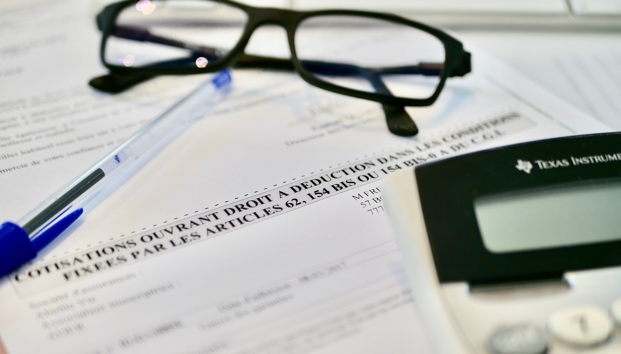 A businesses' desk with a contract to be signed and a pair of glasses. 