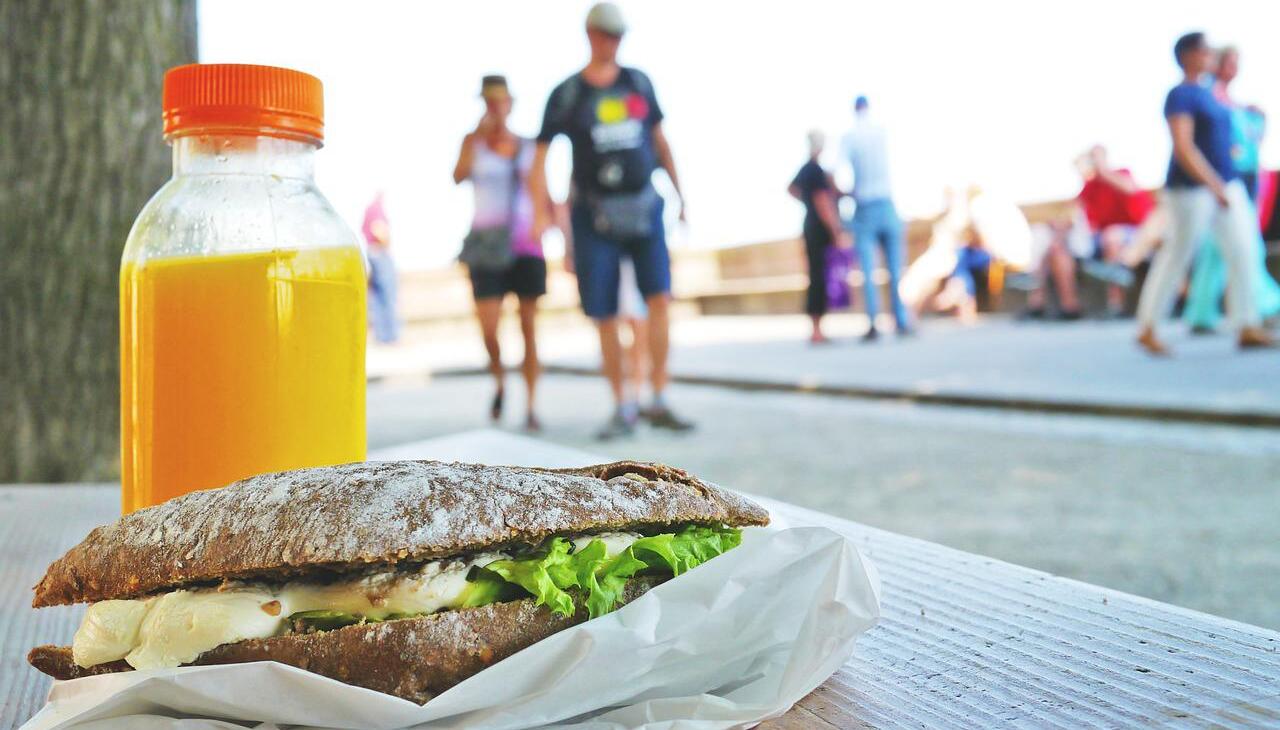 A sandwich and a juice left on a street bank. 