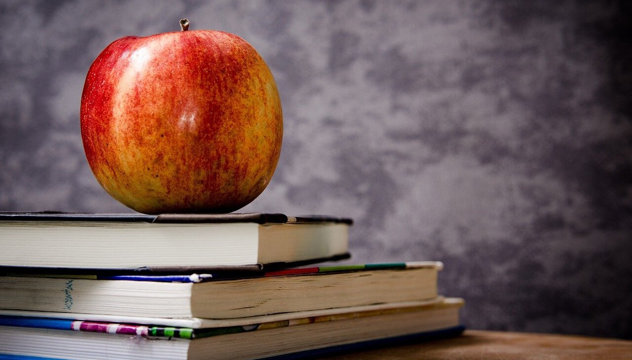 An apple placed on top of some books. 