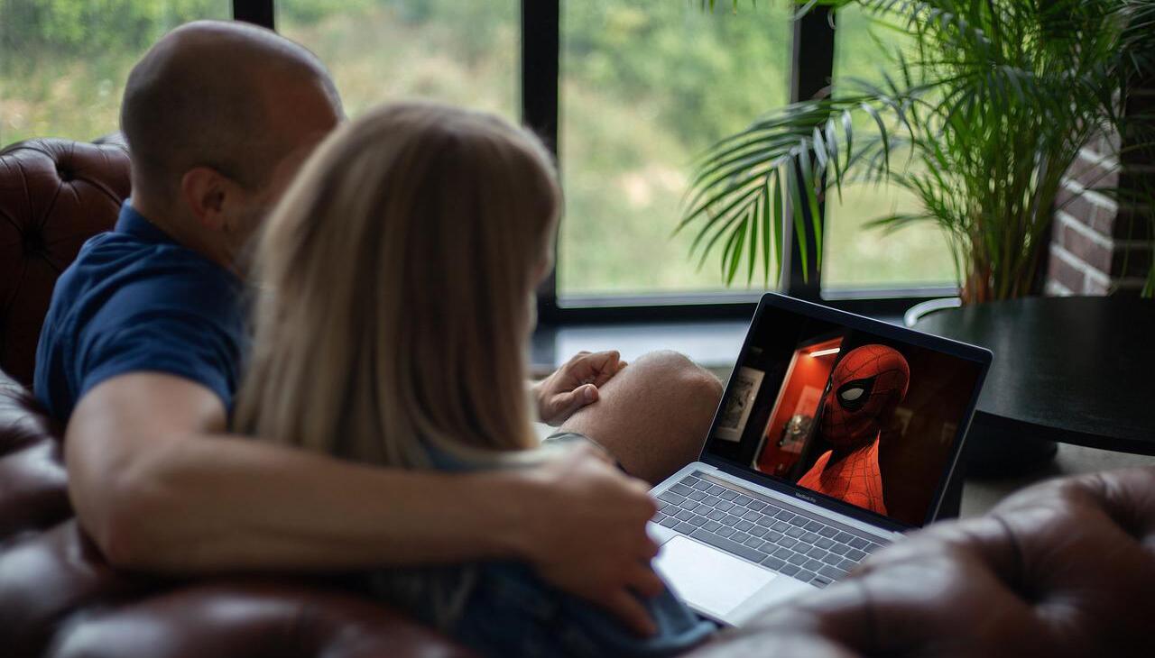 Couple watching a movie on a laptop trough streaming.