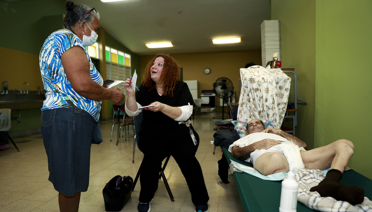 Dr. Lourdes Marrero (C) of the local NGO Haiti Se Pone de Pie attend recent amputee Jaime Martinez (R) who took refuge at the Carlos Colón Burgos Public High School oafter Hurricane Fiona hit the island on September 19, 2022 in Salinas, Puerto Rico. Photo by Jose Jimenez/Getty Images