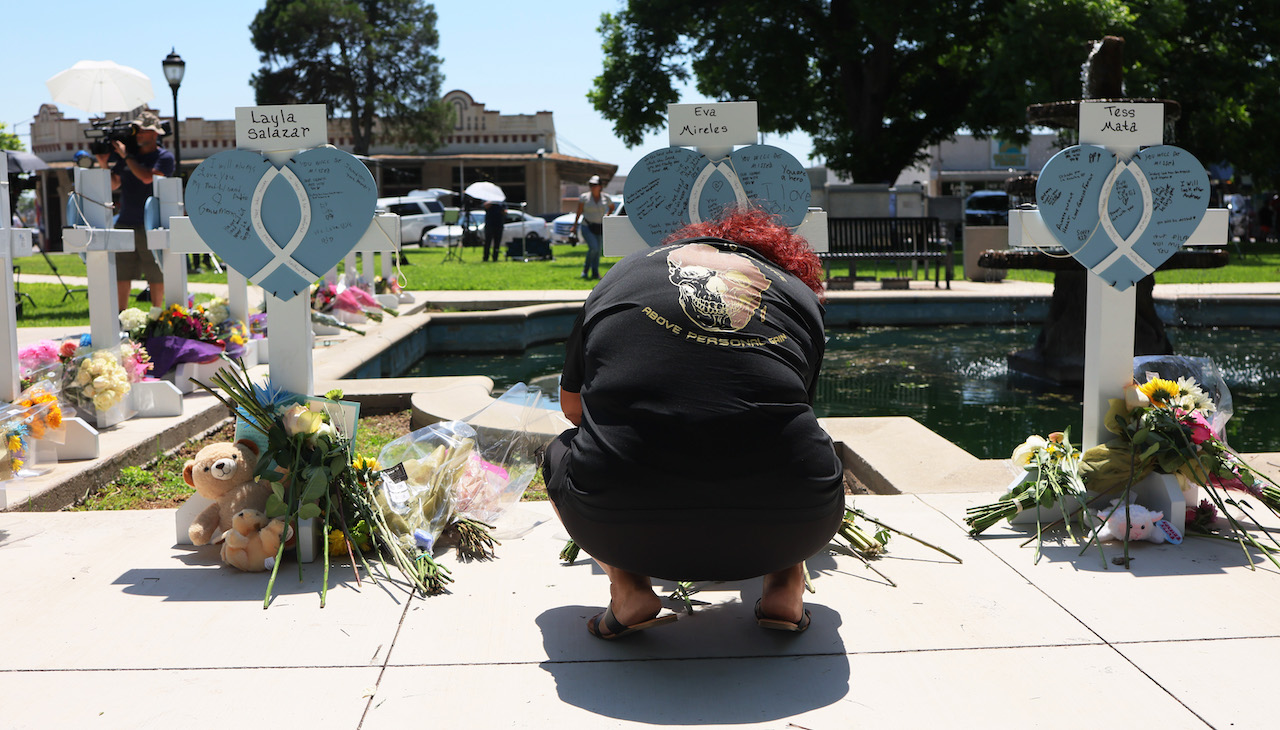 Pictured: A mourner kneels at a memorial for one of the victims of Tuesday's mass shooting at an elementary school, in a park along Main Street on May 26, 2022 in Uvalde, Texas. 