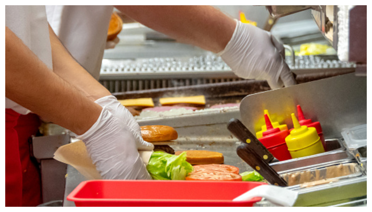 Fast food workers at work, only their hands are shown.