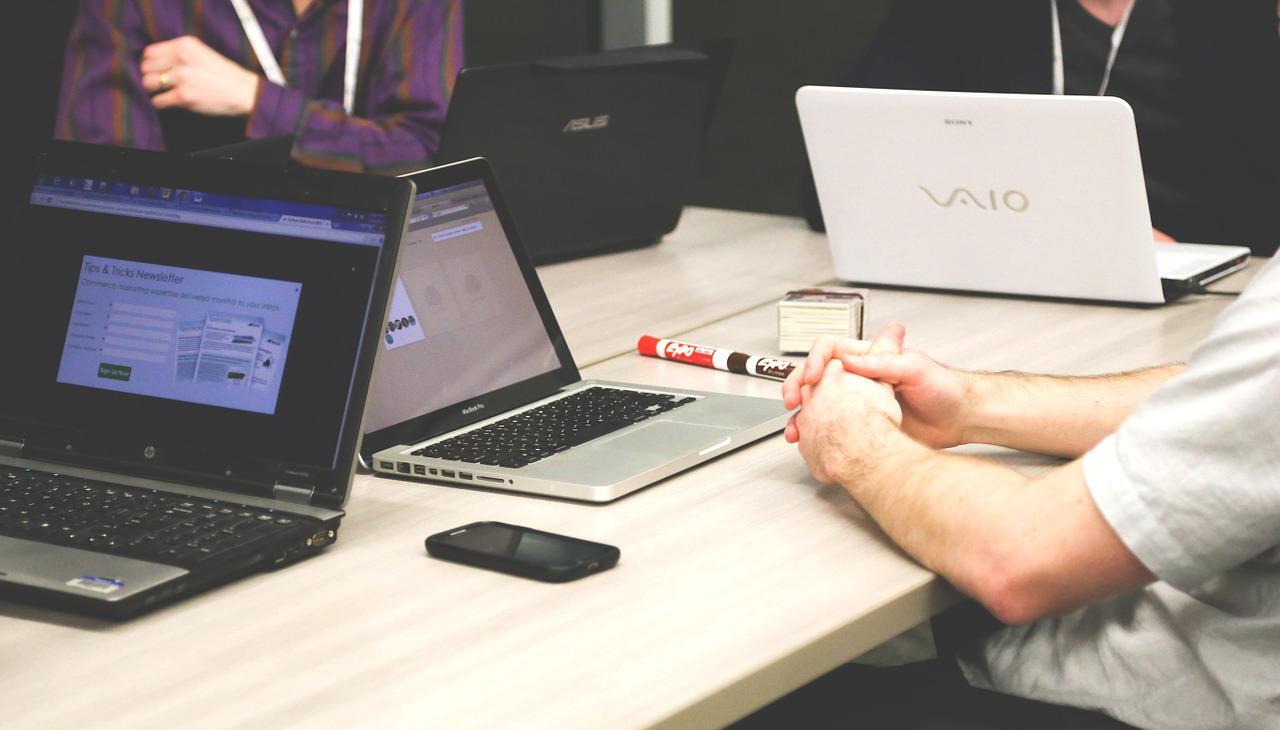 Group of people working in a table full of laptops. 