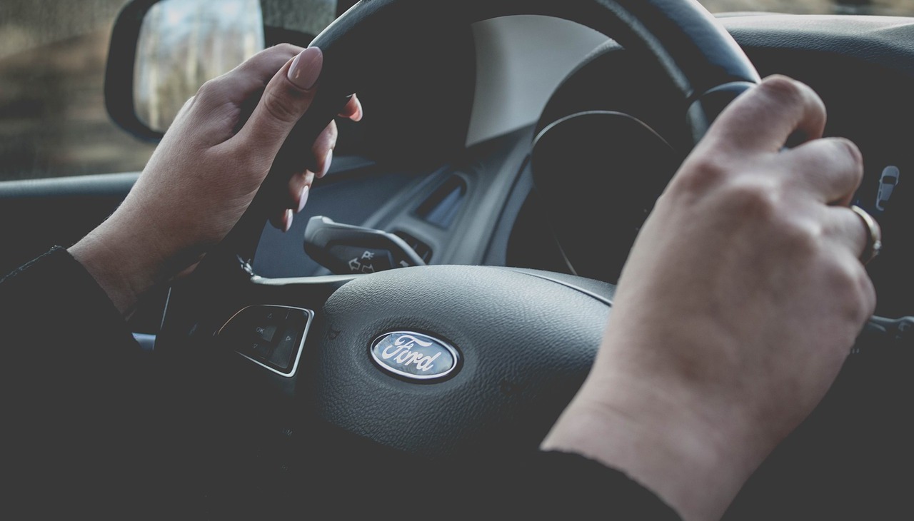 A woman's hands on a Ford's car wheel. 