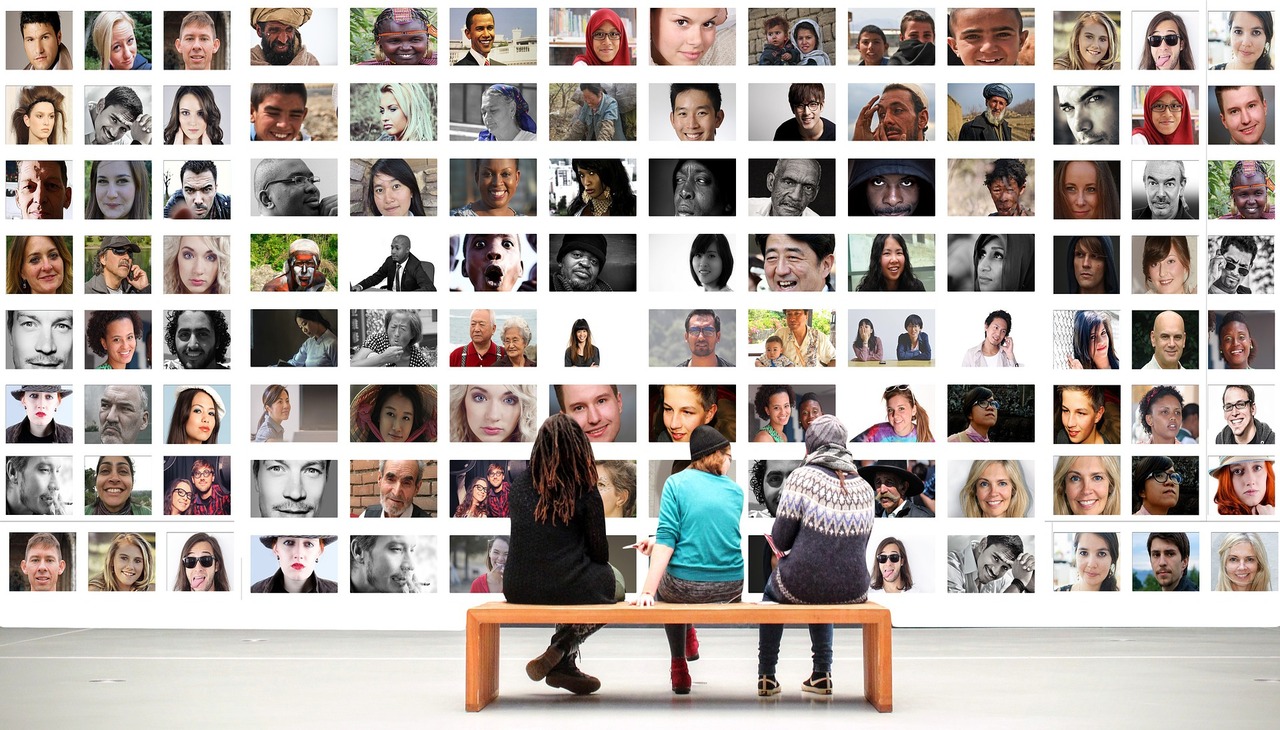 People watching a wall full of pictures on diversity.