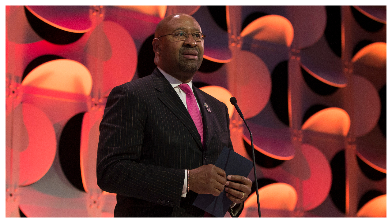 Michael Nutter speaking at a podium. He is an African American man wearing a black suit, looking to the right.