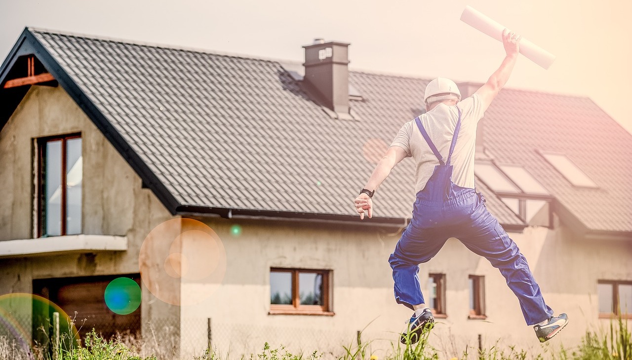 Architect jumps happily in front of a house. 