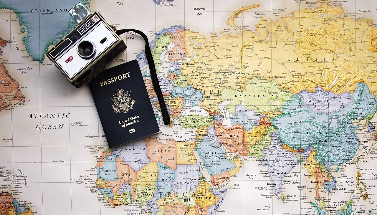 Passport and old camera on top of a map, image to illustrate tourism.