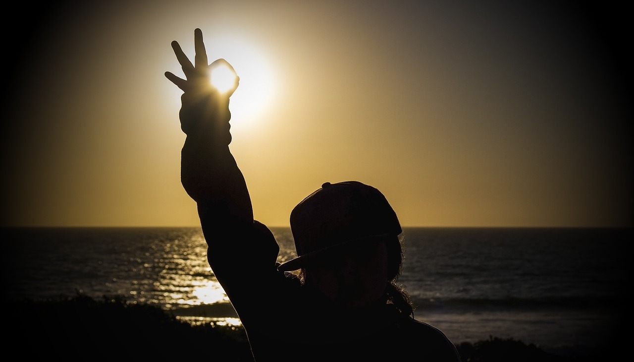 A person doing the ok sign to the sunset. 