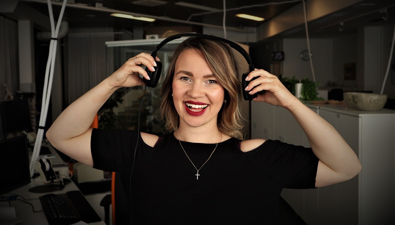 Podcaster smiles in a recording studio. 