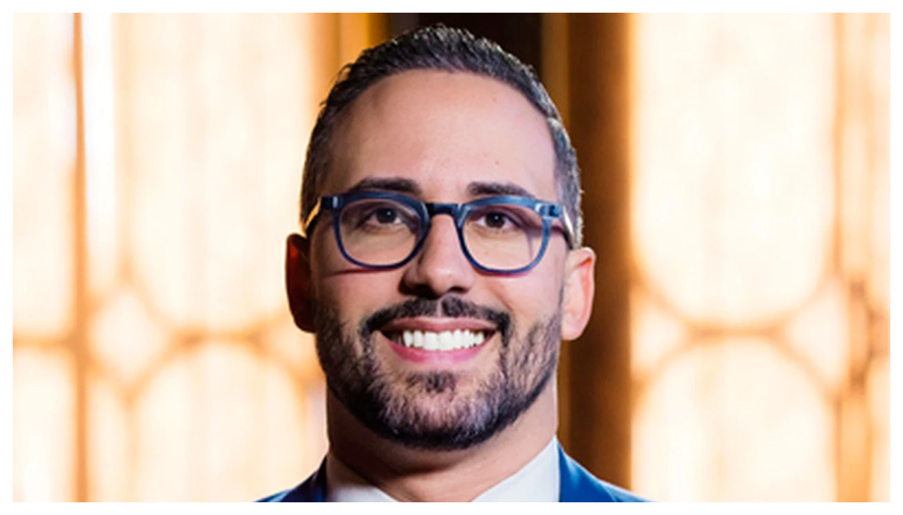 Eric Batista, a Puerto Rican man wearing glasses from the neck up. He is smiling.