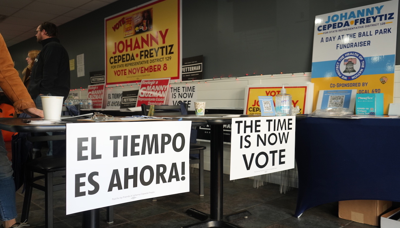 Pictured: Table with two signs (sign 1: "El tiempo es ahora") (sign 2: "The time is now. Vote.")