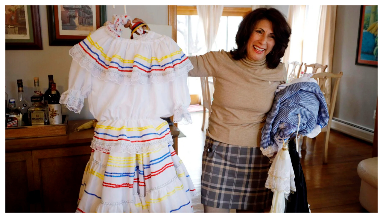 Liliana Ortiz-Bermudez holding up a white dress in the style of a Latin-American dancing dress.