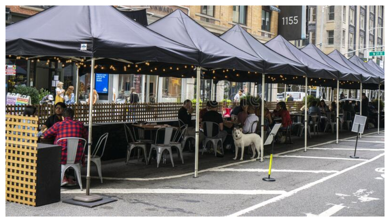 An outdoor dining establishment partly on the street.