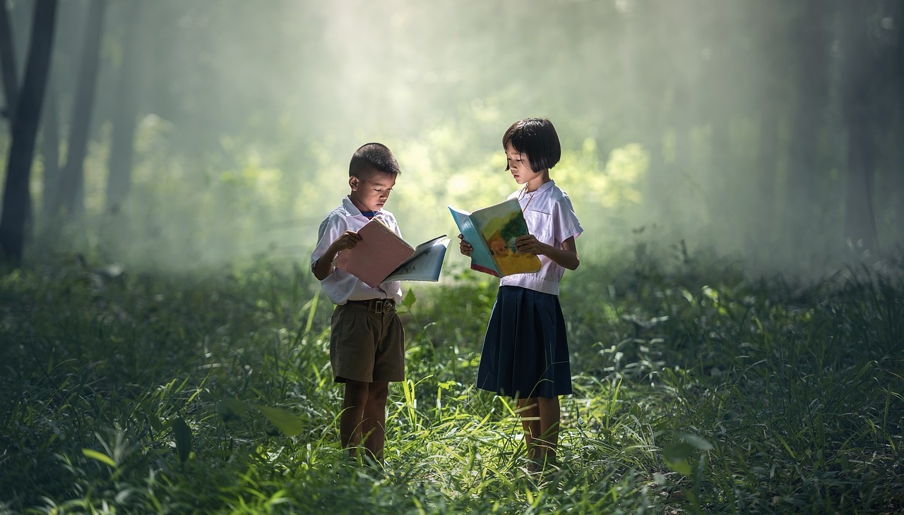 Asian kids reading books on a forrest. 