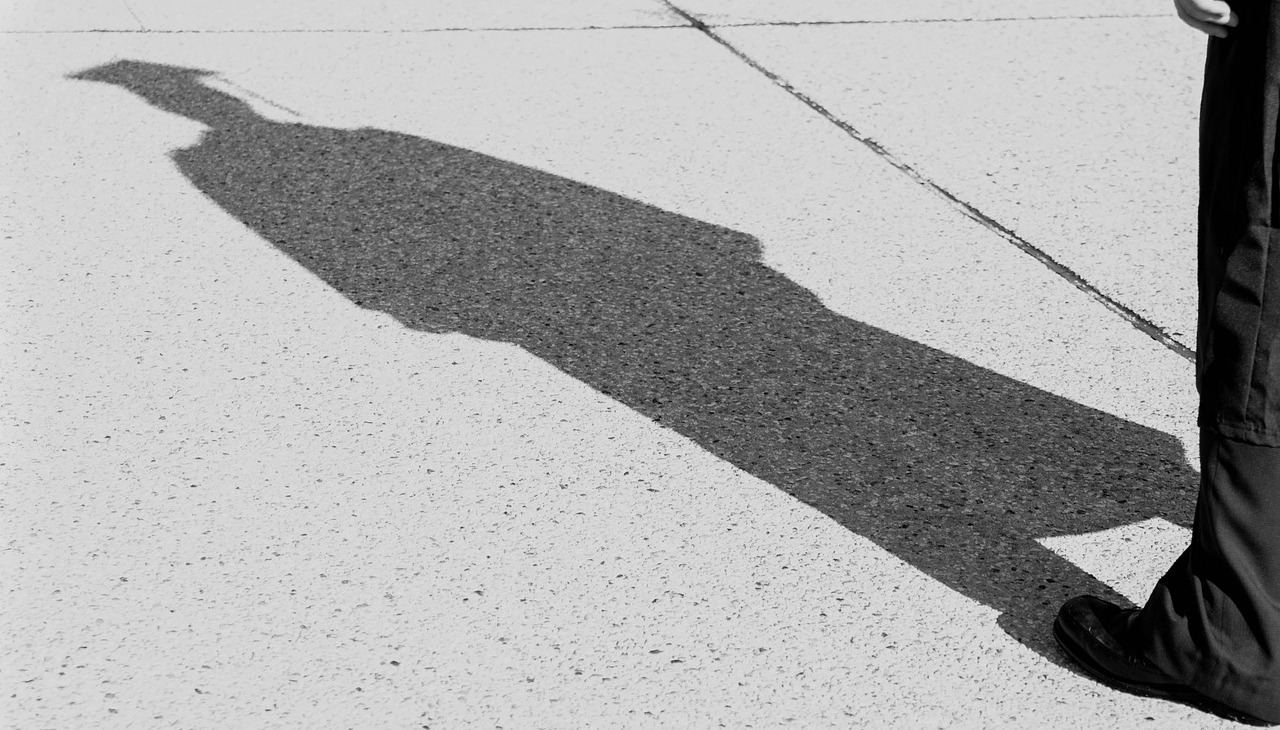 Shade on the floor of a person wearing a graduation hat.