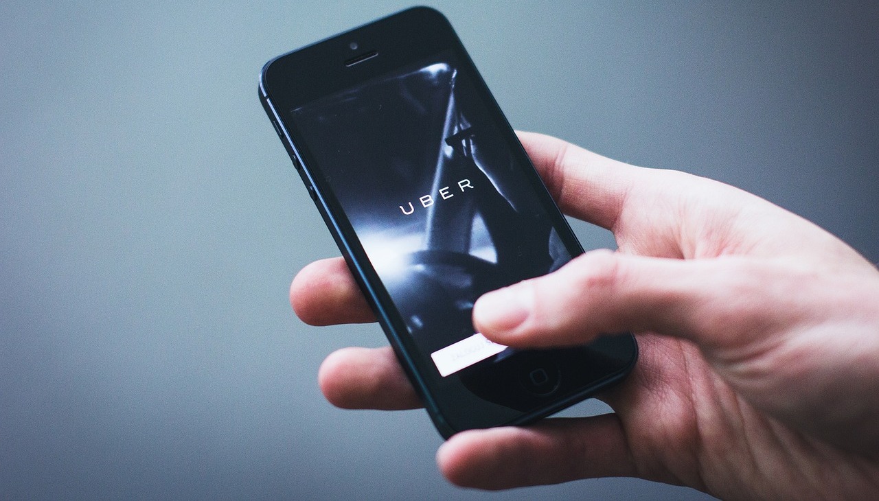 A person holds a cell phone with UBER displaying on the screen. 