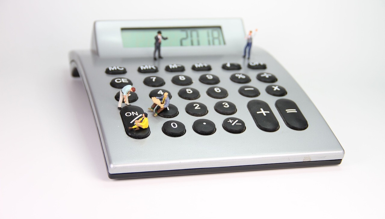 Plastic tolls on top of a calculator, image to illustrate economic recession. 