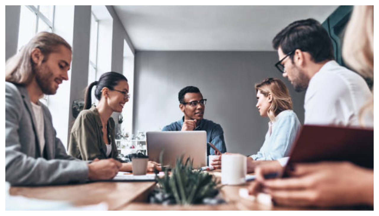 A group of people discussing a topic over a meeting room table.