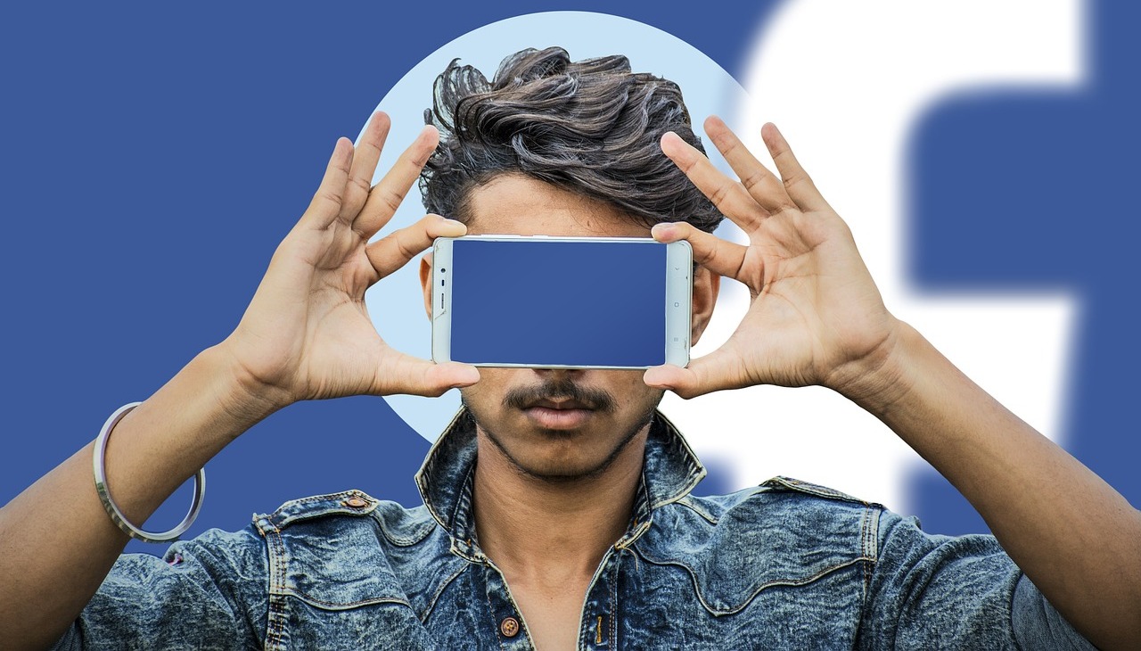 Man covers his face with a cell phone, image to illustrate digital literacy campaign. 