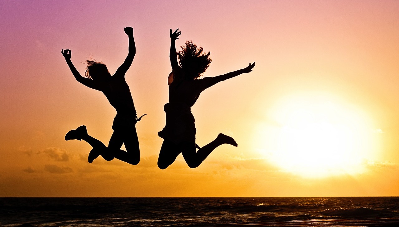 People jumping in the beach during a sunset.