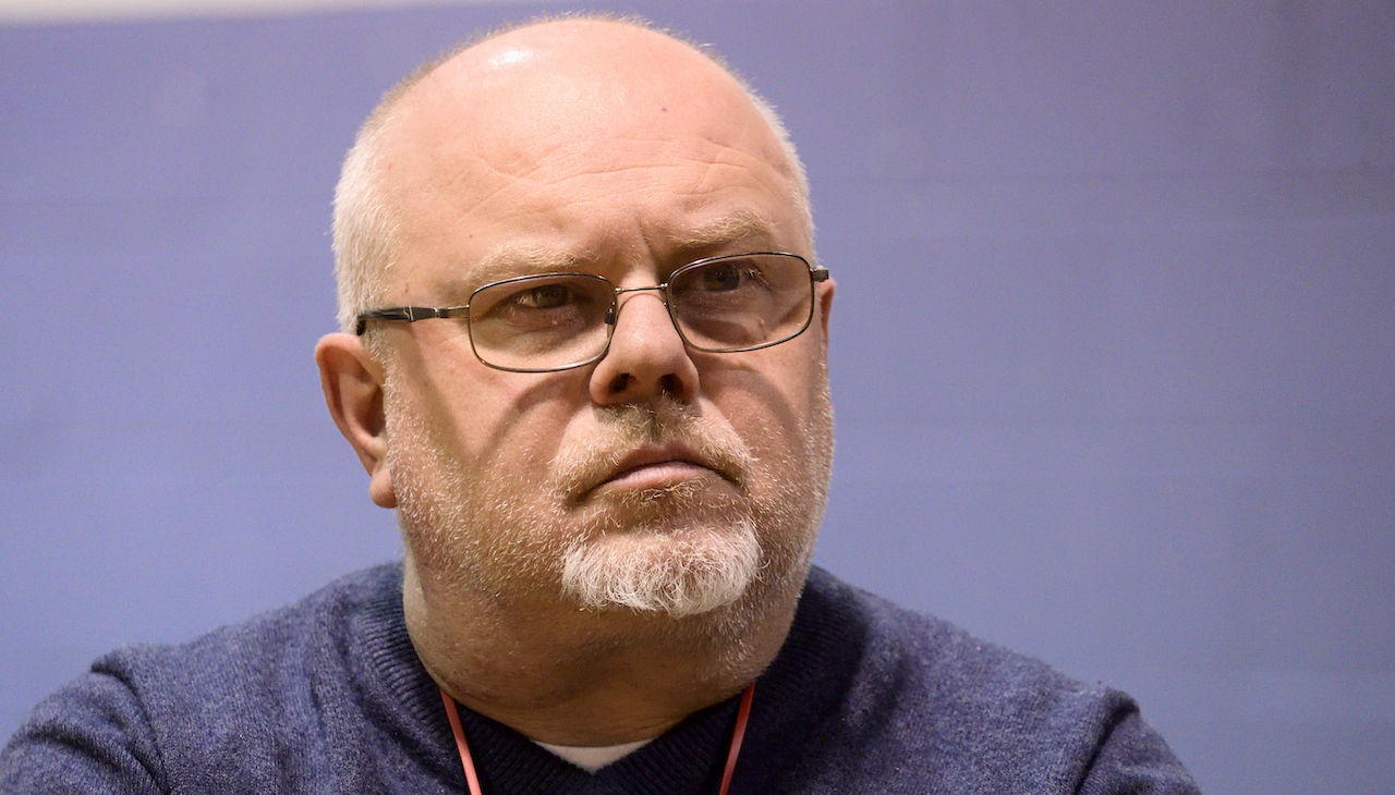 Jose Benitez, a balding man with short cropped gray hair and glasses. He is facing a speaker that is out of view.