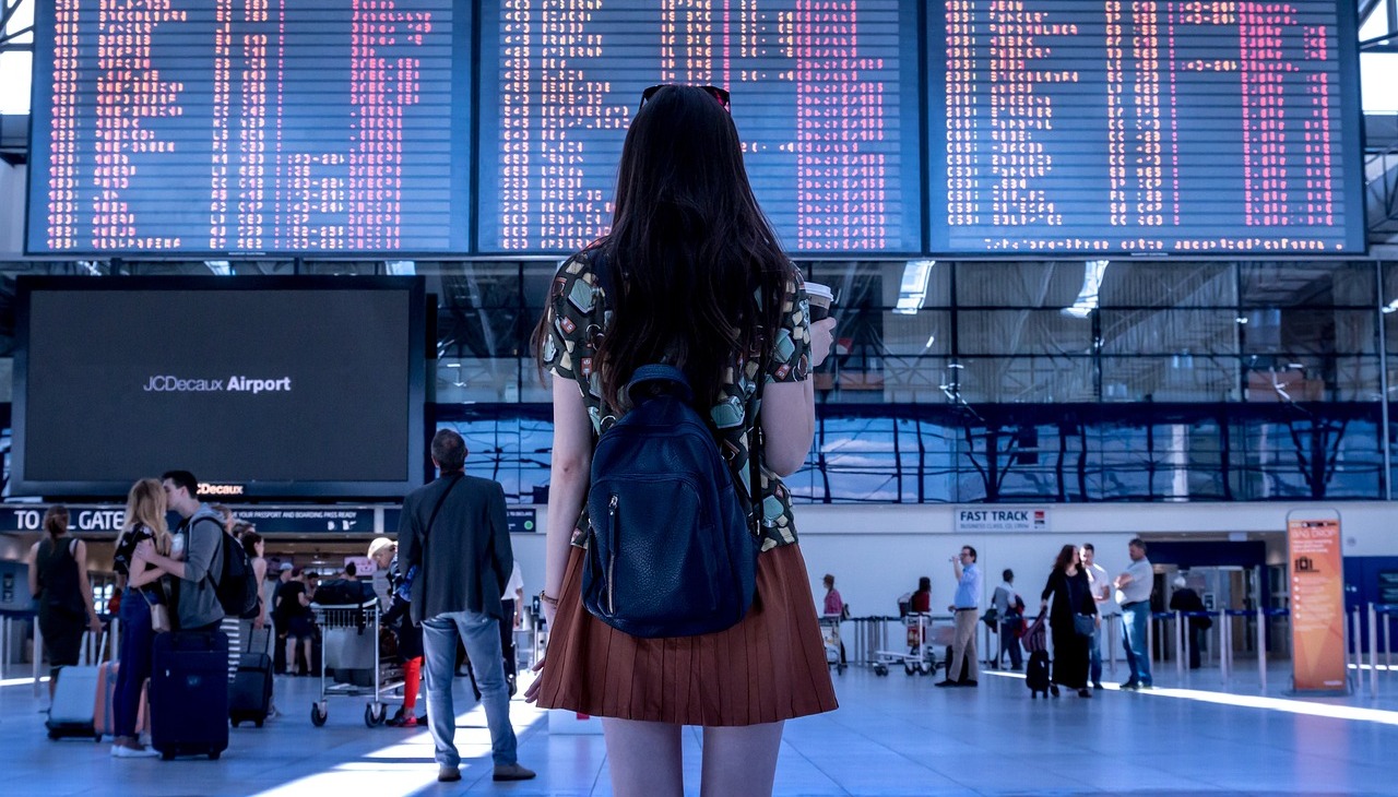 Young girl waiting in front of airport screens. 