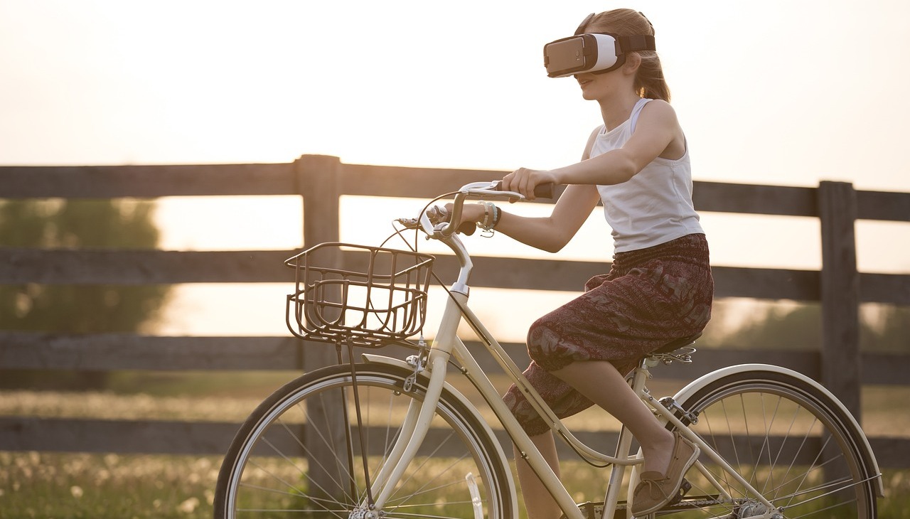 Girl riding a bike wearing a VR device. 