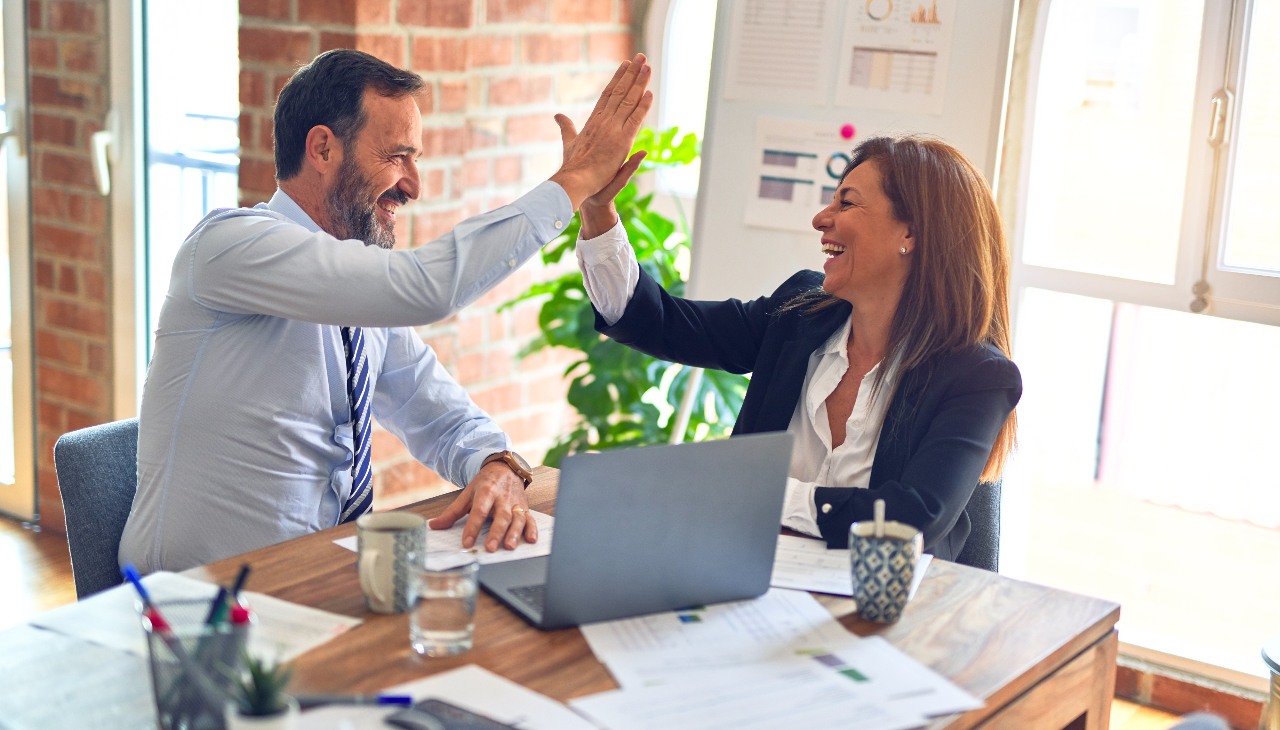 Office workers giving each other a high five. Photo credit: krakenimages on Unsplash