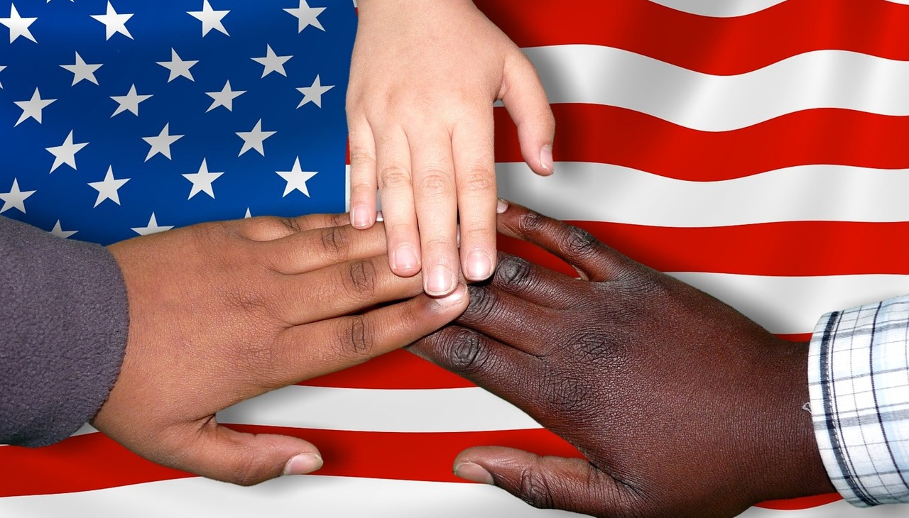 Hands together under the frame of a U.S. flag. Image to illustrate migration. 