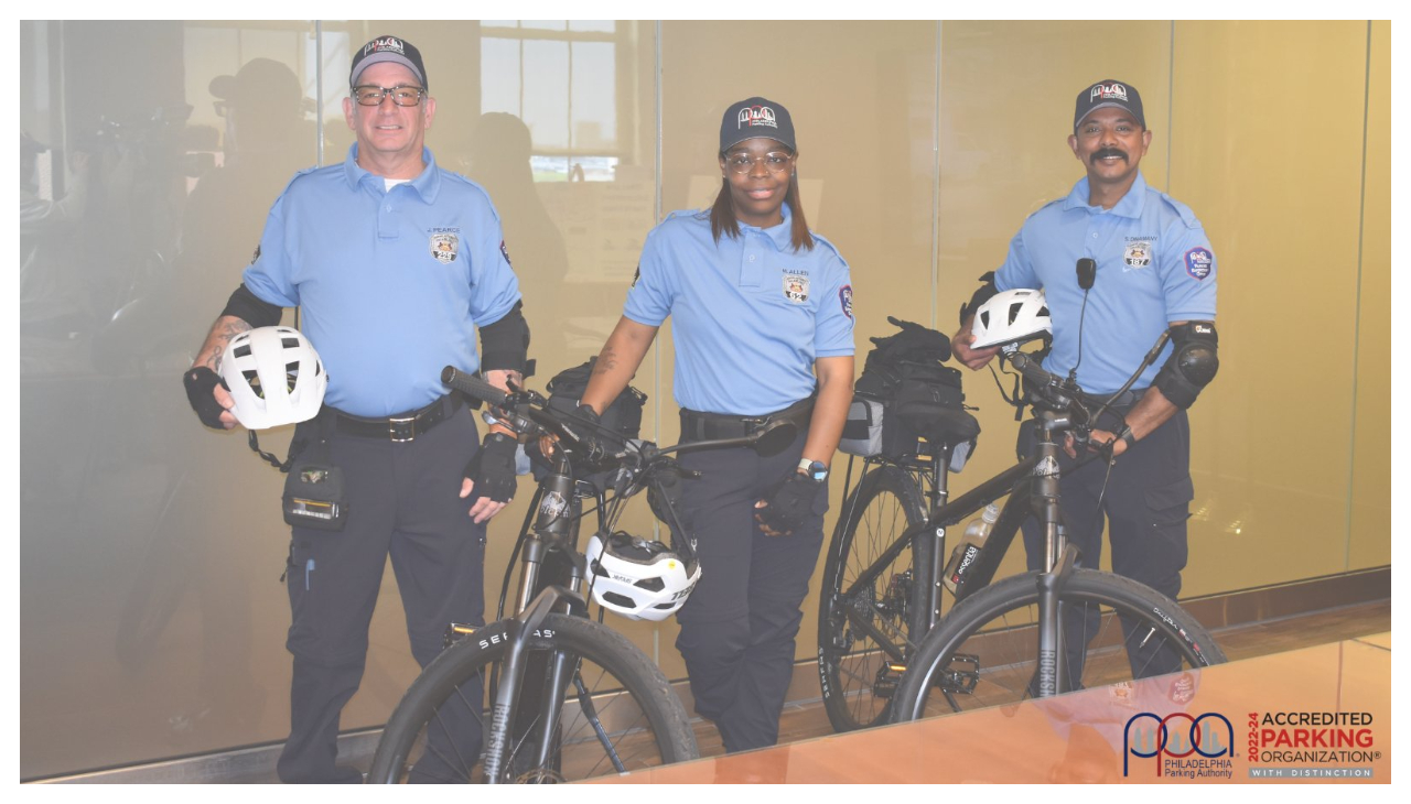 Three of the Bicycle Lane Enforcement unit's members, standing in uniform beside their bicycles.