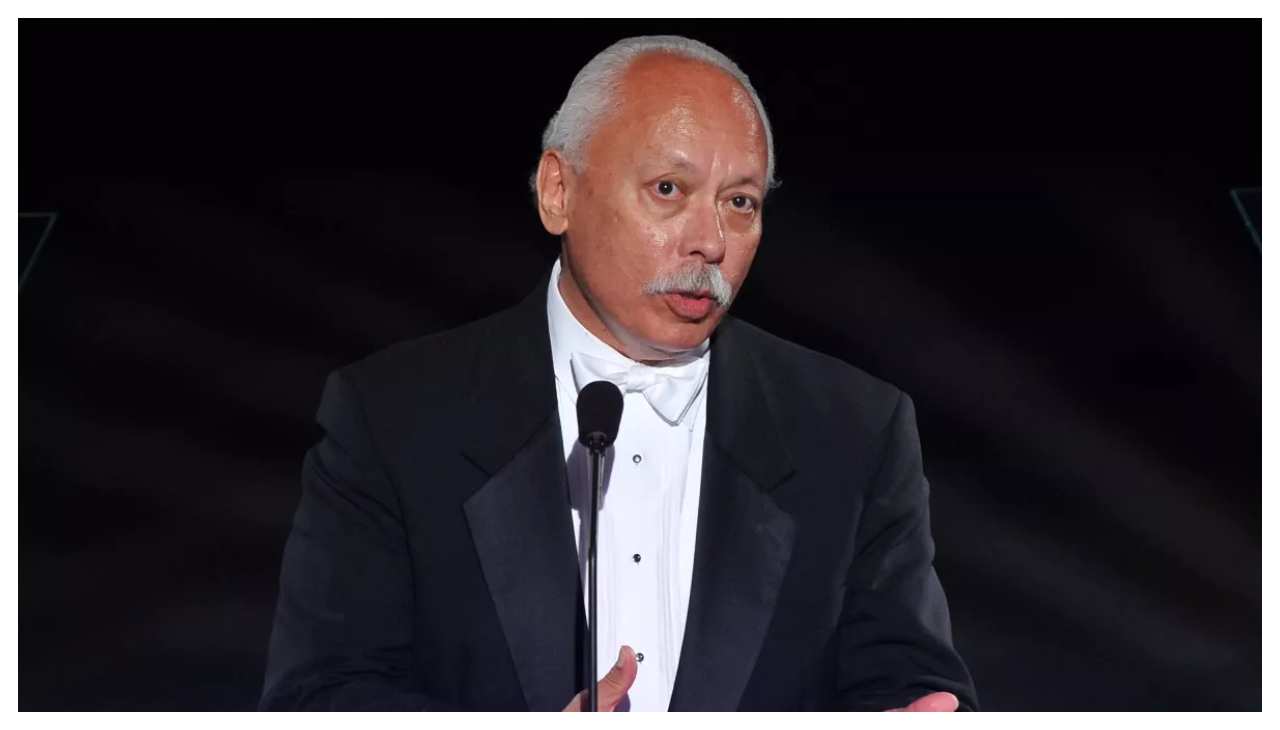 Tony Valdez, a Latino man in a suit speaking at a podium.