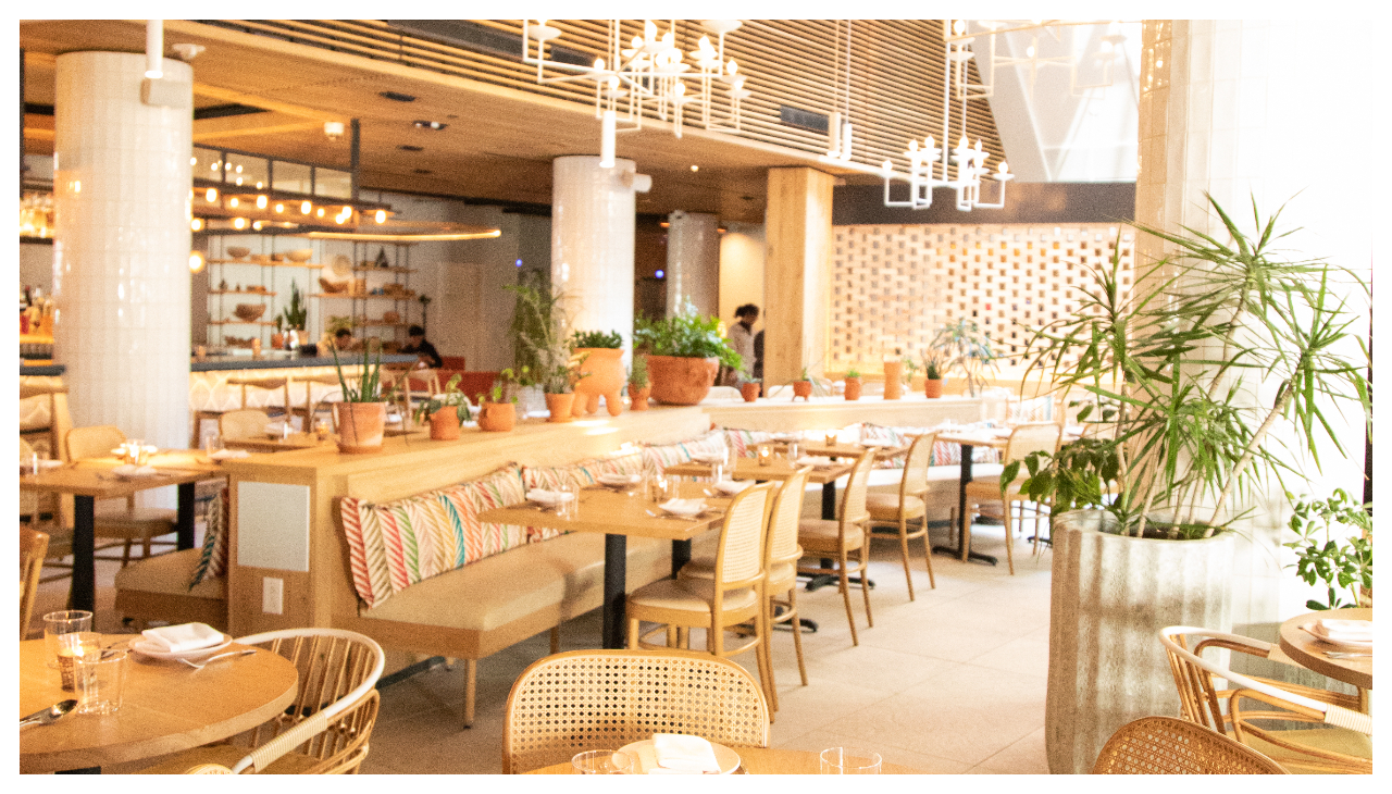 The interior of the Condesa restaurant. It is comprised of light brown interior and numerous light brown chairs and tables.