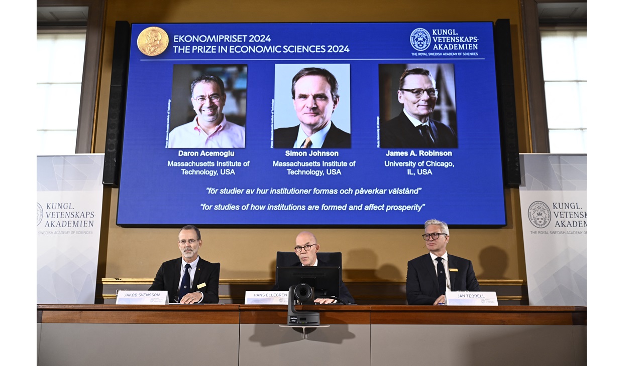 Academy of Sciences permanent secretary Hans Ellegren (C), Jakob Svensson (L) and Jan Teorell of the Nobel Assembly sit in front of a screen displaying the laureates (L-R) Turkish-American Daron Acemoglu and British-Americans Simon Johnson and James Robinson of the 2024 Sveriges Riksbank Prize in Economic Sciences in Memory of Alfred Nobel during the announcement by the Royal Swedish Academy of Sciences in Stockholm, Sweden on October 14, 2024. (Photo by Christine Olsson/TT / TT NEWS AGENCY / AFP)