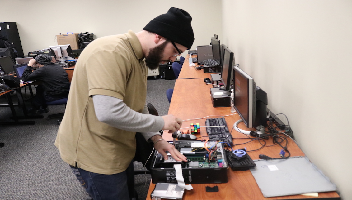 Gabrielle Ramos takes apart a computer as part of his IT training with Project WOW. Photo: Nigel Thompson/AL DÍA News