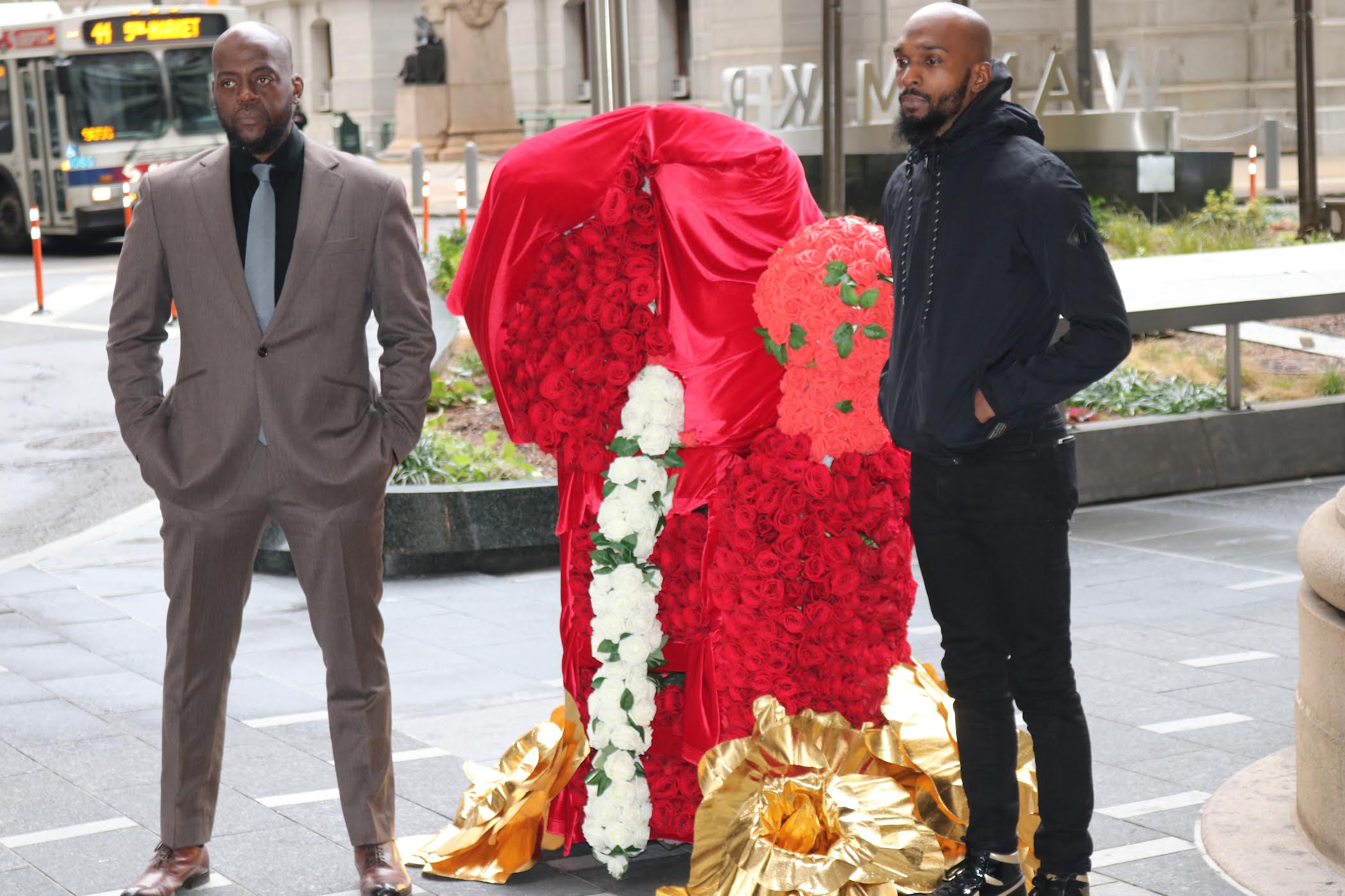 Dawud Bey (left) and Maleek Jackson (right) stand in front of a boxing glove floral scultpure to commemorate the lives of those lost to gun violence in 2021. Photo: Brittany Valentine | Al Día News