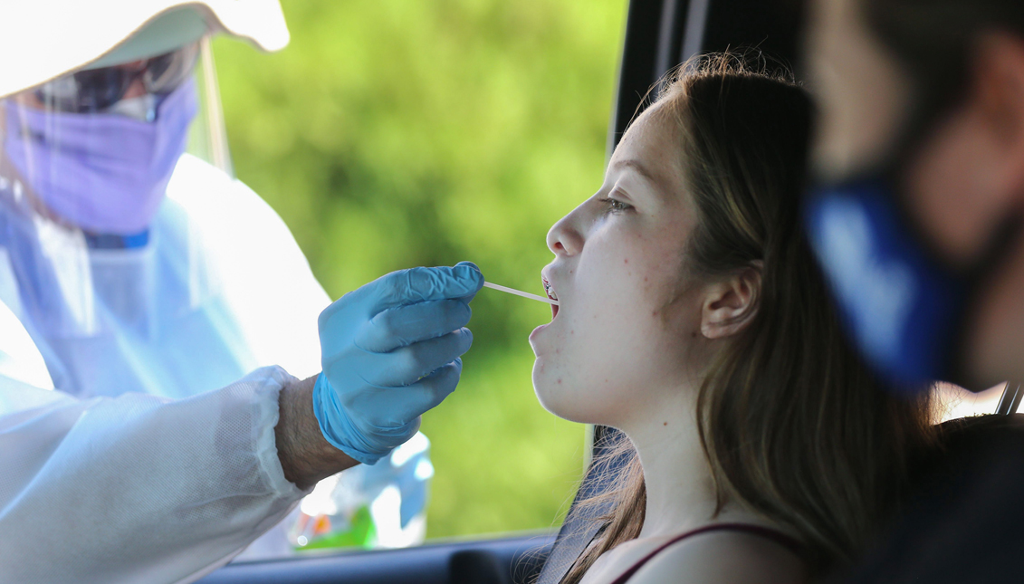 LOS ANGELES, CALIFORNIA - AUGUST 11: A healthcare worker gives a girl a throat swab test at a drive-in coronavirus (COVID-19) testing center at M.T.O. Shahmaghsoudi School of Islamic Sufism on August 11, 2020 in Los Angeles, California. California reported 12,500 new cases after backlogged cases from a data glitch began appearing in the state’s system. (Photo by Mario Tama/Getty Images)