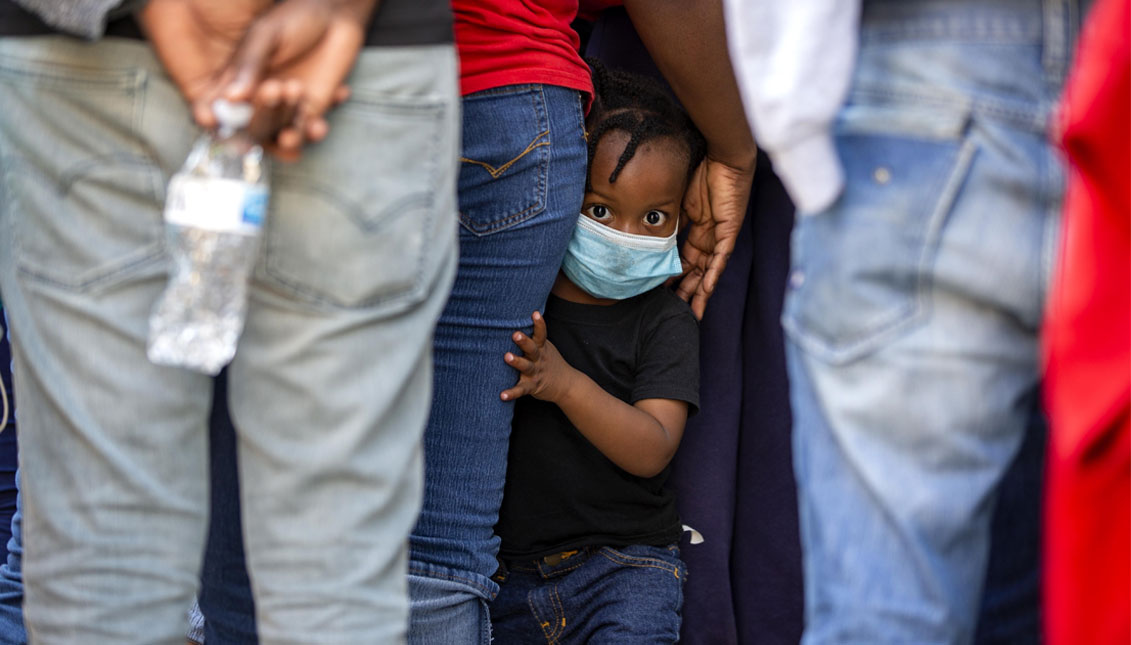 Un niño ve hacia la cámara mientras haitianos que fueron deportados de Estados Unidos se forman para entrar a un hotel en el que serán puestos en cuarentena para frenar la propagación del coronavirus, en Tabarre, Haití, el jueves 23 de abril de 2020. (AP Foto/Dieu Nalio Chery)(ASSOCIATED PRESS)