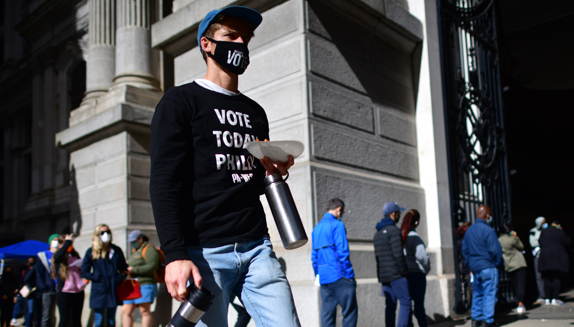 PHILADELPHIA, PA - OCTOBER 27 - A volunteer walks past voters queueing outside of Philadelphia City Hall to cast their early voting ballots. Nearly 3 million Latinx voters have voted early in the U.S. compared to about 1.4 million who cast their votes at this point in 2016. Nearly 500,000 are young Latinx voters under 30. Photo: Mark Makela/Getty Images