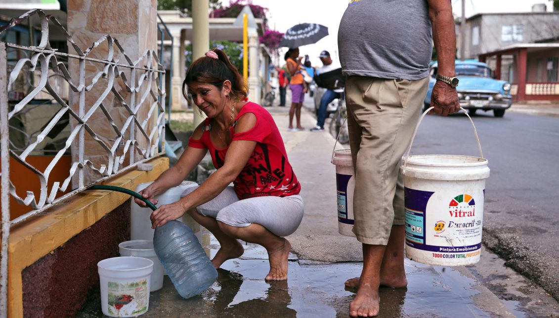 Two people filling containers with water at a neighbor's house, in the province of Ciego de Avila, Cuba on Apr. 3, 2017. EFE/Alejandro Ernesto
