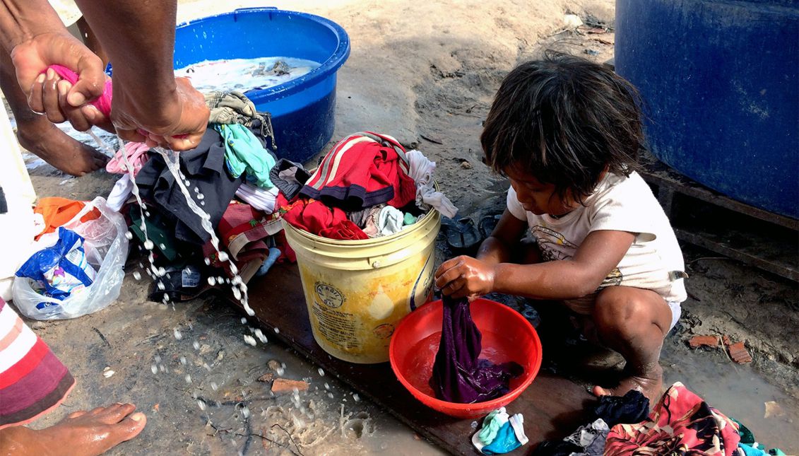 A girl of the Venezuelan Warao tribe washing clothes with her mother outside a shelter in Boa Vista, Brazil, on February 11, 2017. EFE/HRW/CESAR MUÑOZ ACEBES