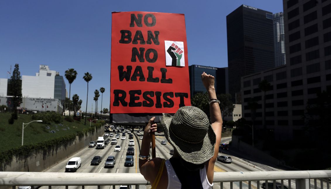 A May Day marcher makes fist while holding up a banner reading 'No Ban No Wall Resist' as they rally in the streets of downtown Los Angeles, California, USA, 01 May 2017. EPA/PAUL BUCK