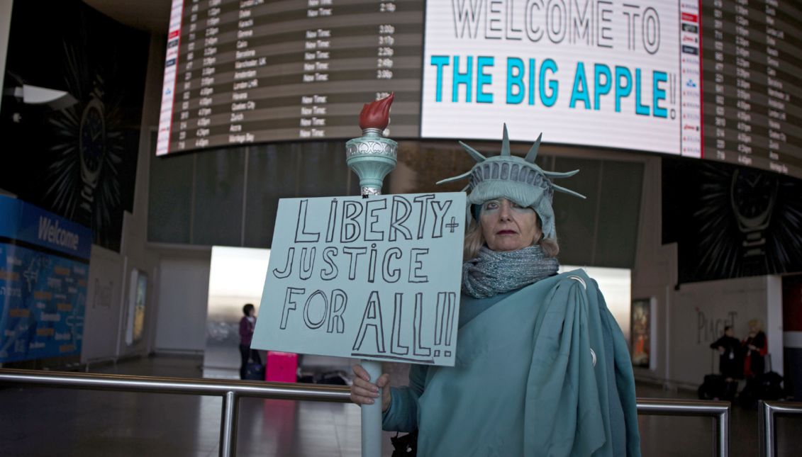 A woman dressed as the Statue of Liberty holds a placard 'Liberty and Justice for All' as she stands inside the arrivals section of Terminal 4 at John F. Kennedy International Airport in Queens, New York, USA, 04 February 2017. EPA/JOHN TAGGART