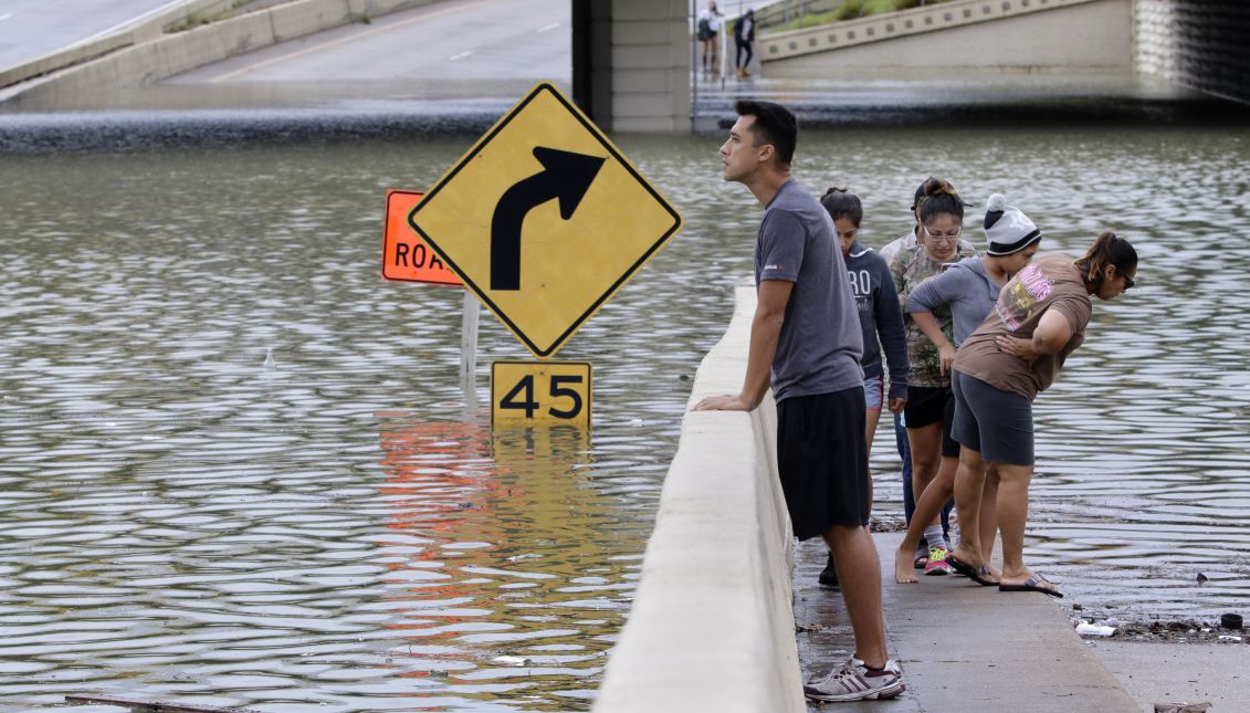 Spectators view the submerged highway interchange of Interstate 10 at Post Oak Road during a break in the rain in Houston, Texas, USA, 27 August 2017. EPA/MICHAEL WYKE